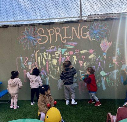 Toddler Montessori students expressing themselves artistically in our courtyard on a beautiful spring day