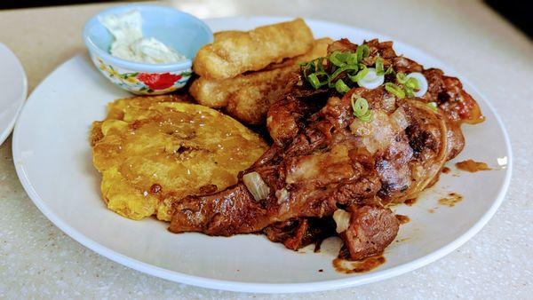 Chivo guisado, tostones y yuca frita