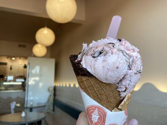 Chocolate covered strawberry ice cream in a chocolate waffle cone