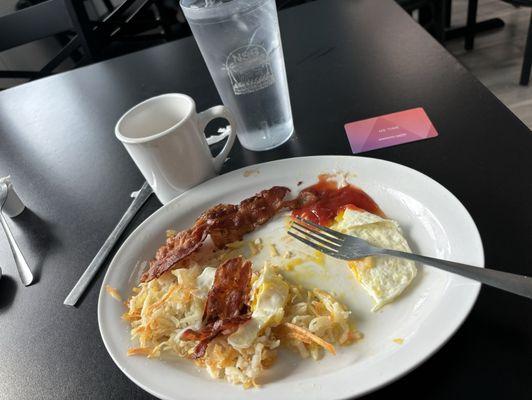 Eggs over medium, bacon and hash browns with a side of coffee and water