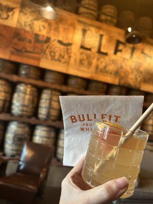 Elderflower Fizz cocktail drink and lounge area barrel wall.