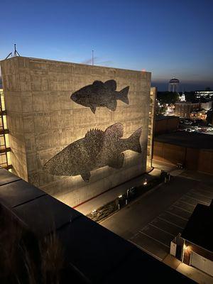 Cool art piece. Tiny metal medallion "scales" shimmer in the breeze. Located on the side of the parking deck.