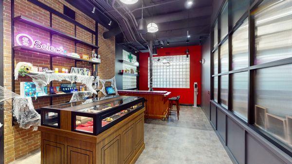 Retail interior with neon sign, cobwebs, and glass display cases.