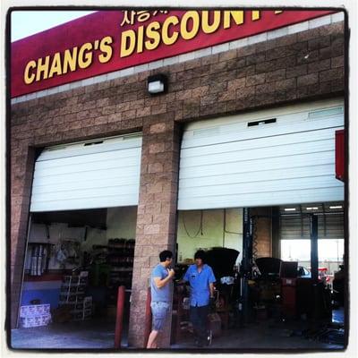 In front of his shop, he is talking with customer.