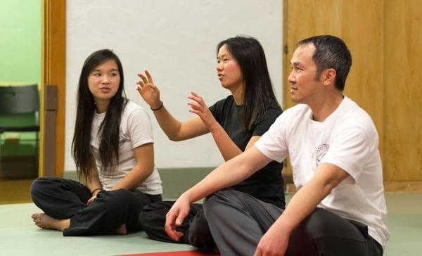 Adult students discuss fighting concepts and theory at a seminar led by Sifu Adrian De Silva.