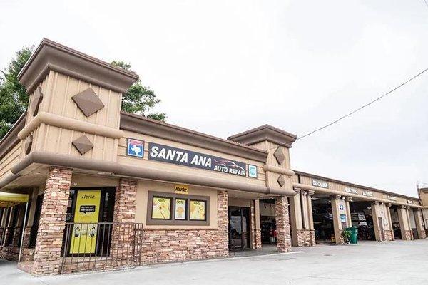 "Santa Ana Auto Repair" shop exterior with beige walls, wooden beams, and a prominent blue sign...