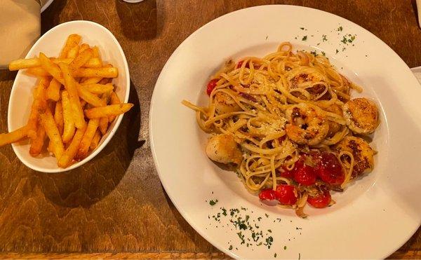 Summer seafood pasta dish with a side of fries.