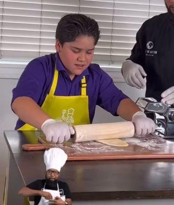 Child making pasta from scratch and Chef guiding him