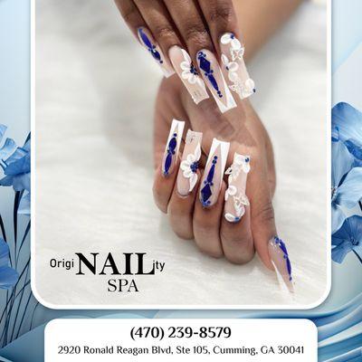 Soft pink nails with delicate white flowers and subtle blue charms, capturing the essence of spring's beauty in a chic and elegant manicure