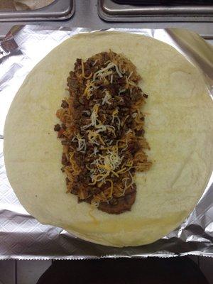 Close up on large size ground beef taco with re fried beans, shredded cheese, homemade rice and home made ground beef