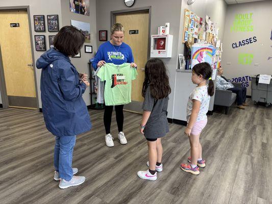 Receptionist Maggie presents the birthday girl with a choice of colors for her birthday gift t-shirt.