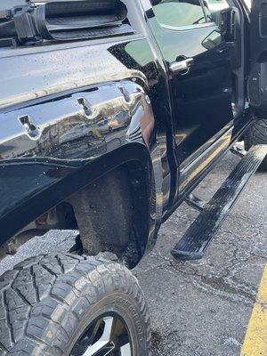 The opposite side of the vehicle still showing dirt on the step rail and tires directly after being washed by the service workers.