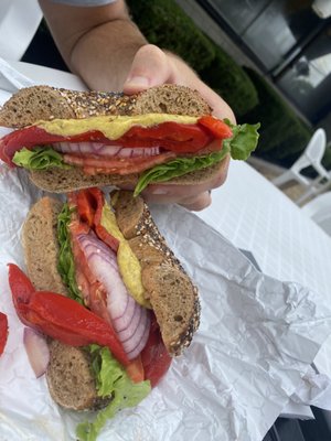 Whole wheat everything bagel with lettuce, tomato, onion, roasted peppers, and yellow mustard.