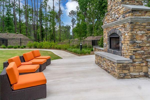 a concrete patio with orange couches and a stone fireplace at Sterling Creek