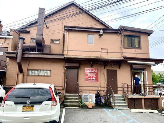 Parking lot in the back with a back entrance into the restaurant where the man is going in.