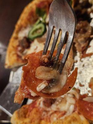 Close-up of a fork holding a piece of the Pizza Suprema.