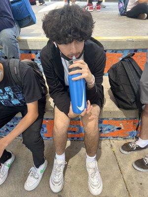 Fellow young student drinking H2O to rehydrate after a long day of partaking in academical activity. What a jolly good fellow.