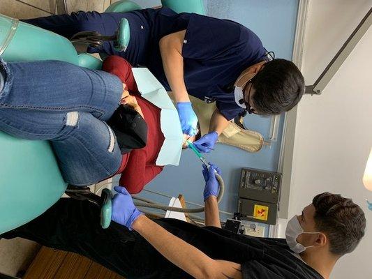 Dr. Park performs extraction on patient with help of dental assistant Ernesto Flores.