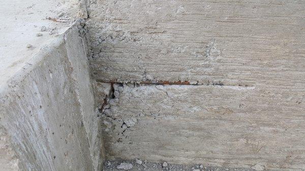 Exposed rebar on newly poured foundation.  A pre-pour inspection would have caught this defect.