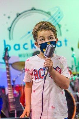 A boy singing with a rock band at a summer camp at Backbeat Music Academy in Protland, OR