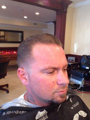 Slicked back pompadour on top with bald taper fade on sides and back..