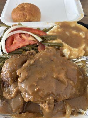 Smothered pork chops mashed potatoes and green beans.