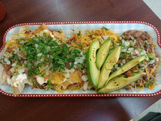 Tamales plate with rice and beans and avocado topped with pico onion cilantro and cheese