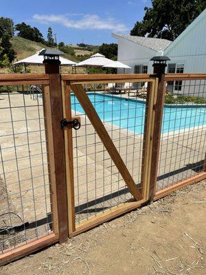 "Rancher's Delight" Custom redwood-framed livestock panel fill fence with solar post cap lights.