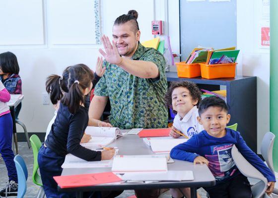 Elementary teacher high fiving student during a classroom assignment