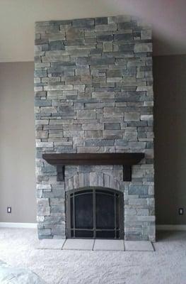 Fireplace done in Echo Ridge Country Ledgestone by Boral Cultured Stone with wood mantel and custom masonry fireplace doors.