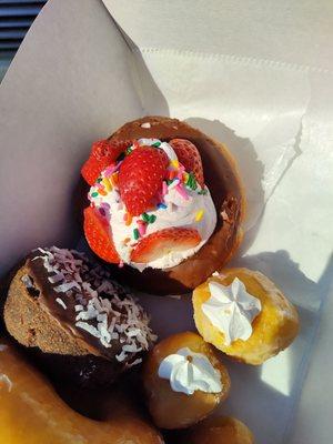 Strawberry cream chocolate, cream puffs and a chocolate coconut donuts.