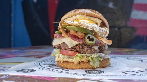 Jalapeno Bacon Burger with a bacon/beef blend patty, crispy bacon, fried egg, grilled jalapenos & garlic aioli