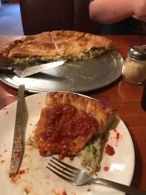 The stuffed pizza, slice in front cover in the sauce.