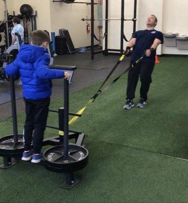 Northville CoachMeFit Client, Frank pulling his son on a backwards sled drag.