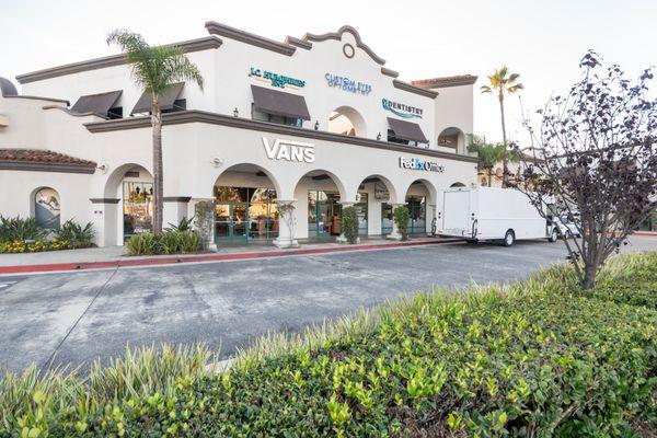 Alternate angle of Custom Eyes Optometry's logo alongside neighboring businesses in Costa Mesa, CA..