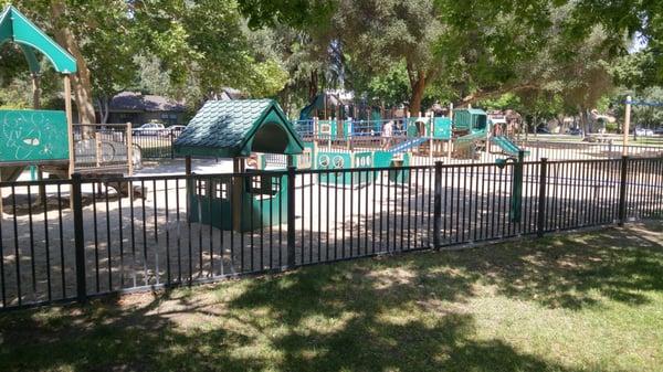 Toddler play area, semi fenced, in front of larger big kid playground.