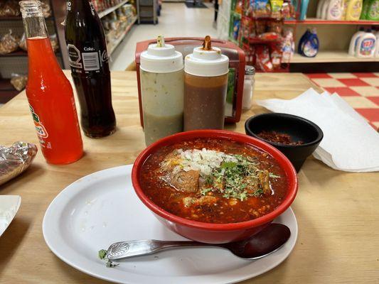 Menudo is prepared with the onions and cilantro red chilly flakes.  Tall coke and a watermelon Jarrito.