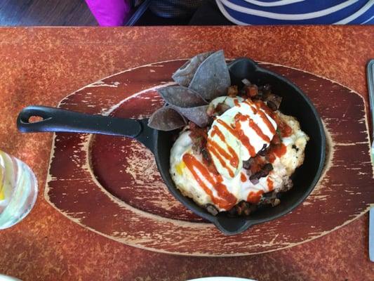 HUEVOS RANCHEROS: blue corn tortillas, avocado cream, black bean salsa, pico de gallo, cilantro sour cream, sriracha, duck fried potatoes