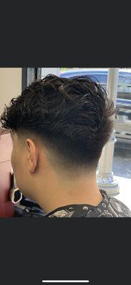 Full wavy/curly hair cut down to compliment his head shape. Low fade blended up to complete this cool style.