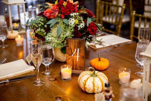 Centerpieces in white pumpkins and table decor completed by Rose Garden Florist!