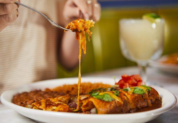 Veggie Enchiladas To Go. Spinach, onions, zucchini, red bell peppers, serranos, roasted green chiles, corn & cheese with Ranchero Sauce.