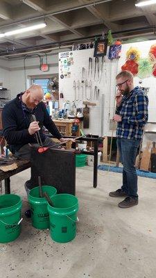 Jesse, owner of JJ Gaffers shaping an ornament with my husband blowing the glass.