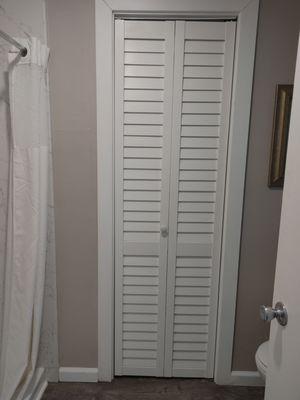 Small closet with hangers, a fan, extra linen, and a pillow.