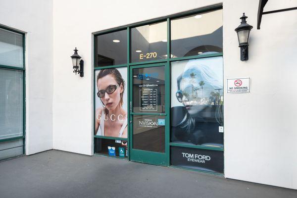 Entrance of Custom Eyes Optometry with stylish Gucci and Tom Ford eyewear advertisements.