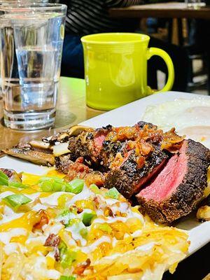 Steak and eggs with loaded potatoes.