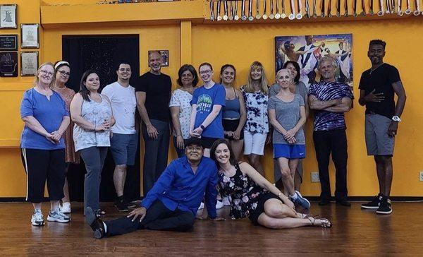 Dance students with the owners/instructors in a ballroom studio.