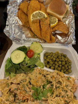 Fried fish with shrimp pasta, green peas, side salad and a dinner roll.