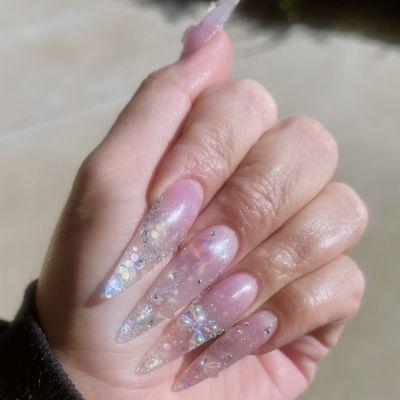 Encapsulated iridescent glitter long almond nail with iridescent gems/stones.