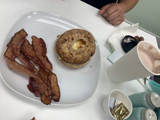 Bagel with bacon in the side.