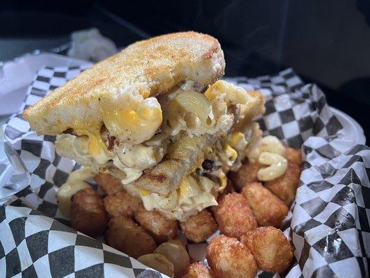 Bacon Mac-daddy. Grilled cheese on sourdough stuffed with bacon Mac-n-cheese over tots 100% fire!!